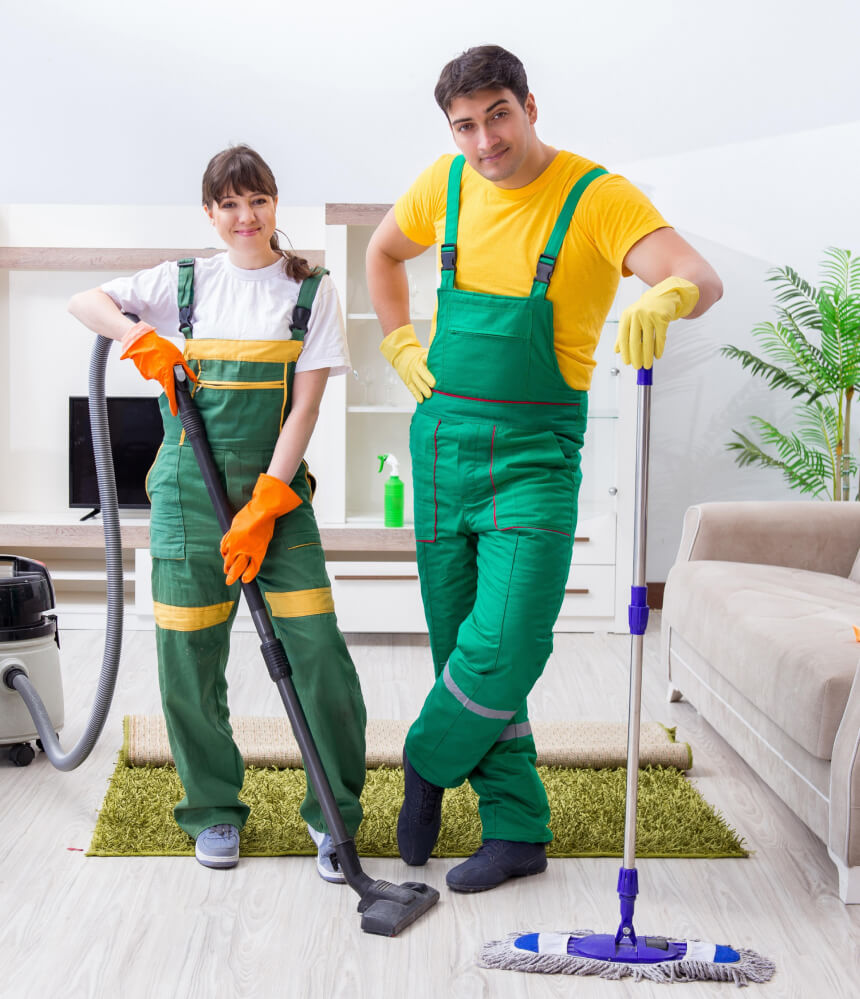 Two cleaners with a vacuum and mop in a living room.