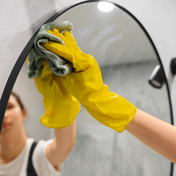 Cleaner polishing a bathroom mirror.