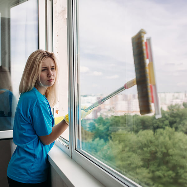Cleaner washing a large window with a squeegee.