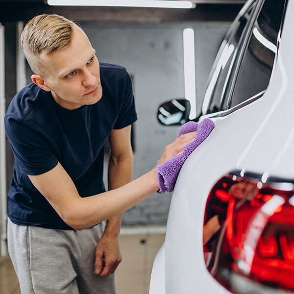 Worker polishing a car exterior.