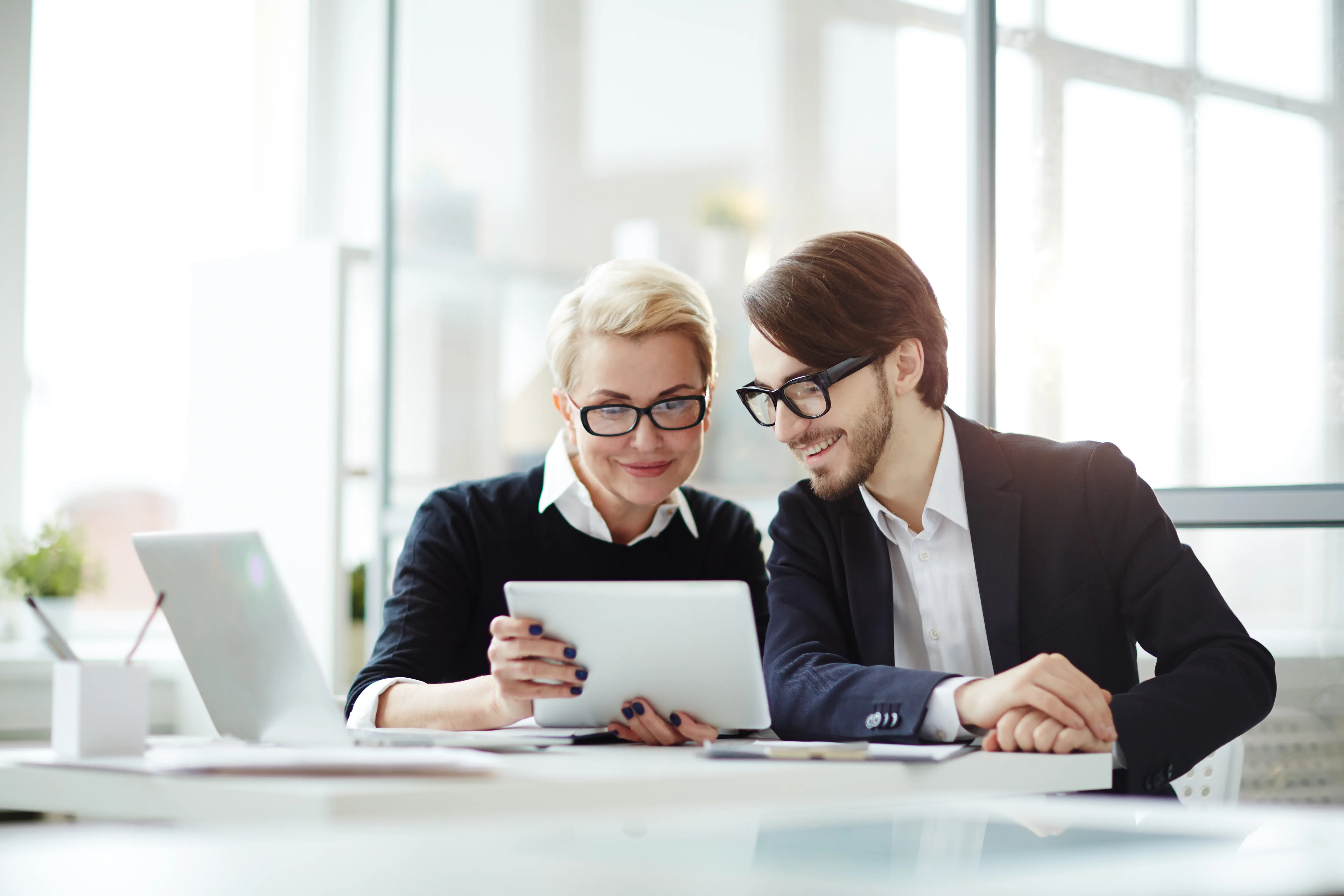 Deux professionnels consultant une tablette ensemble, illustrant la réalisation d’interviews vidéo en entreprise.