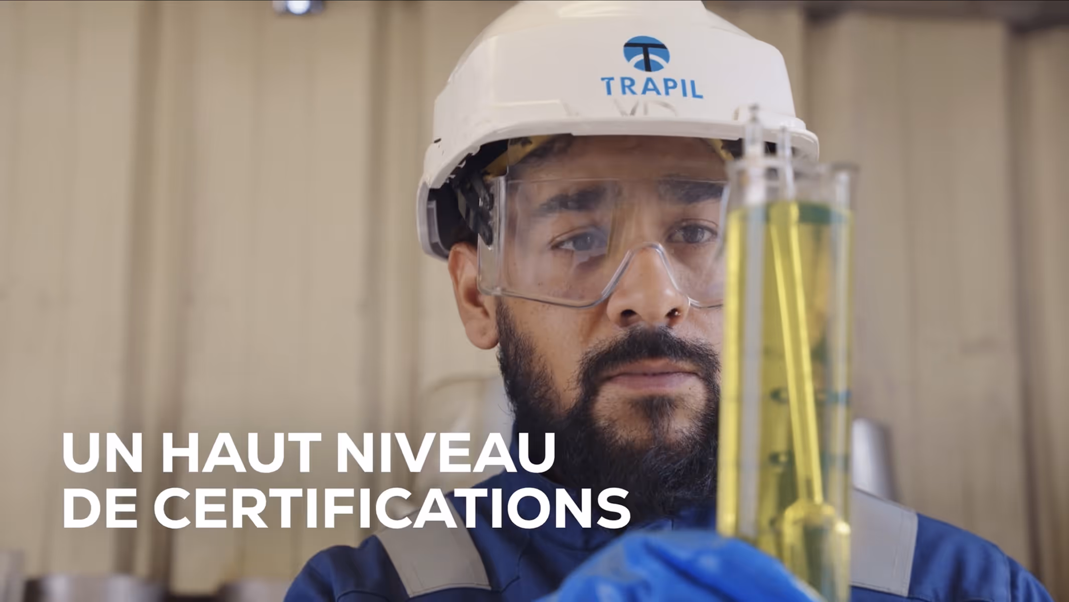 Un homme portant un casque et des lunettes de protection manipule des tubes à essai dans un laboratoire.
