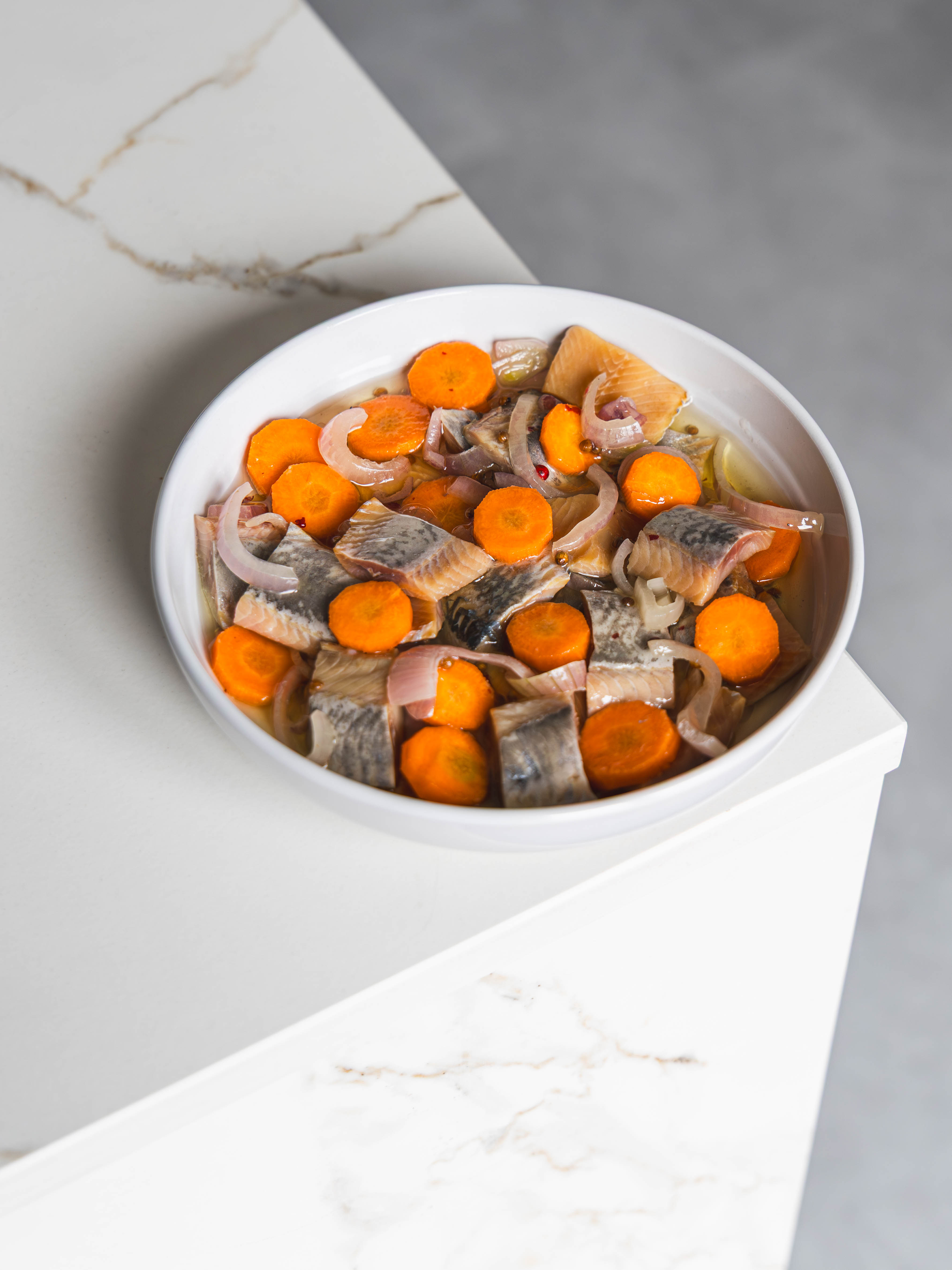 Boisson glacée rafraîchissante servie dans un verre transparent, garnie de glaçons, de framboises et d’une tranche de citron. Le verre est posé sur une table, avec un fond flou évoquant une ambiance estivale et lumineuse.