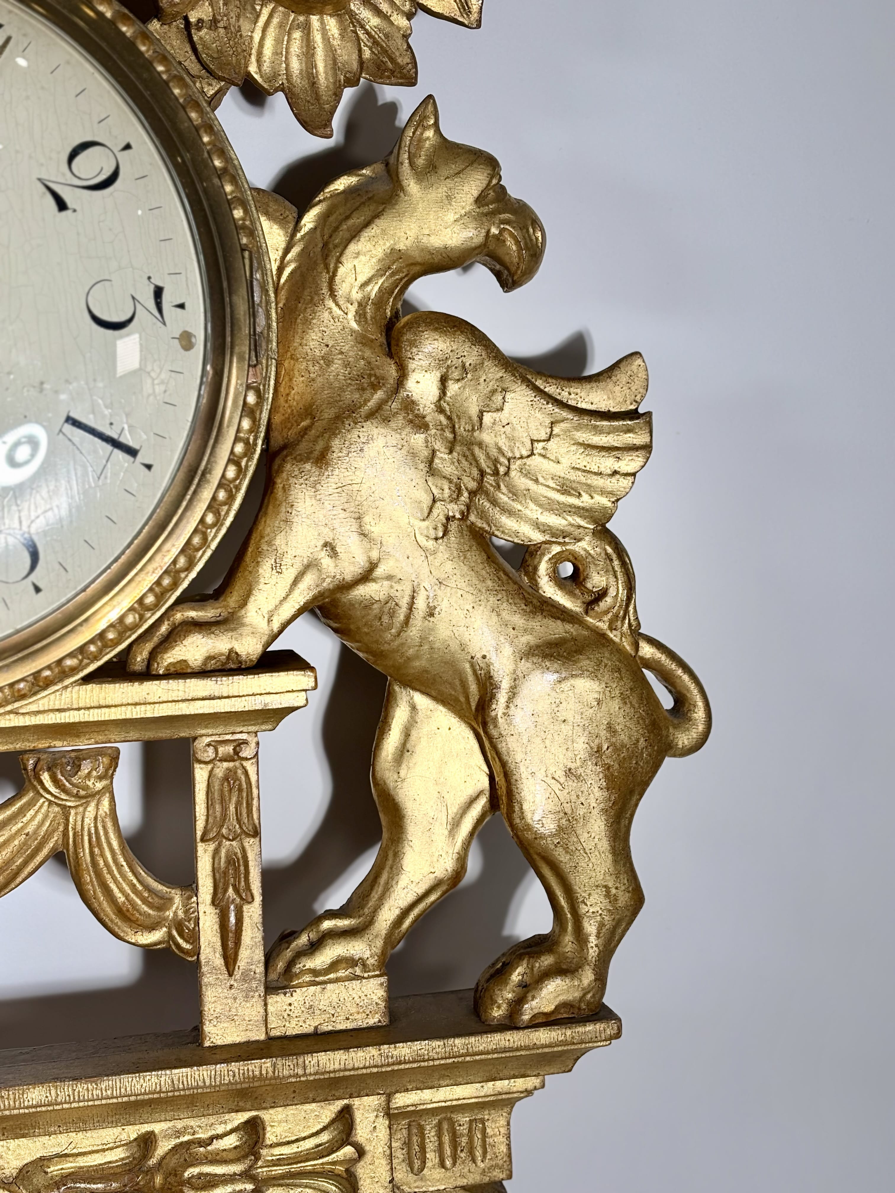 Grande pendule murale aux griffons ailés en bois doré, Suède, XIXe siècle 