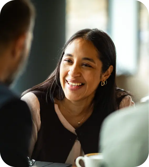 Professional woman smiling during a face-to-face meeting over coffee.