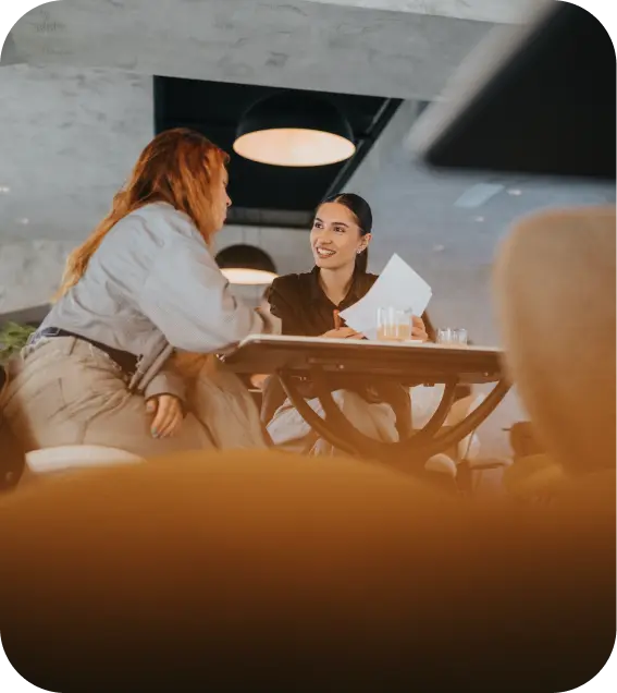 Professional woman smiling during a face-to-face meeting over coffee.
