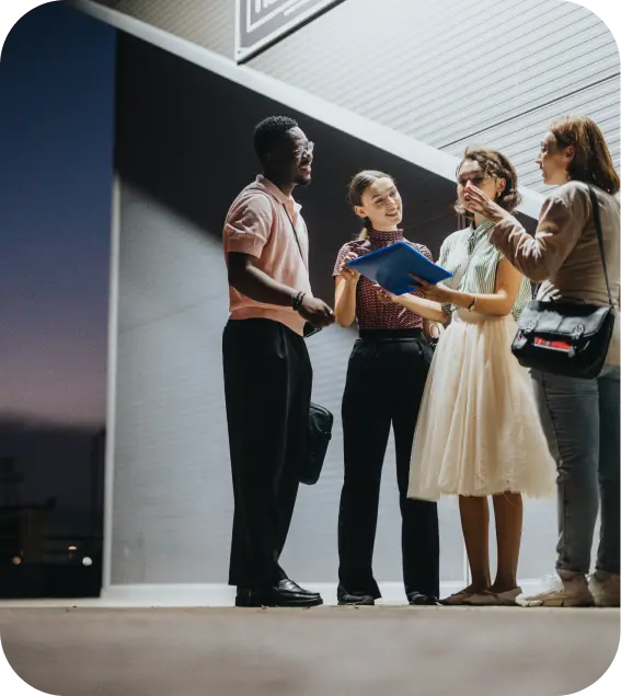 Group of professionals standing outside an office building, discussing documents and collaborating.