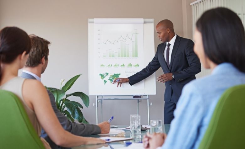 Graphic showing a business leader presenting global expansion strategies on a chart to employees in a boardroom meeting.