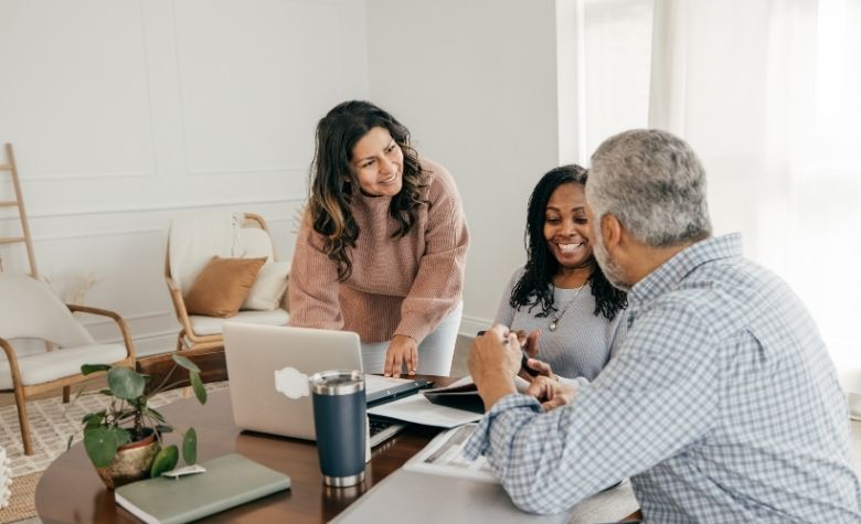 Graphic showing a team meeting where colleagues discuss setting up health benefits for a startup around a laptop in a bright office.