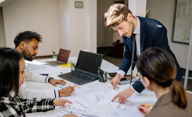 Graphic showing a U.S.-based team discussing FX fees and how they can cut hidden international payroll costs. 