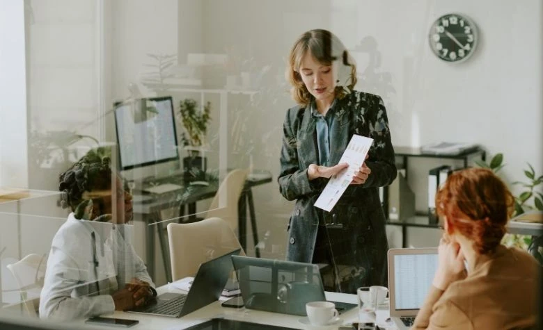 Graphic showing an HR or operations lead reviews employment documents with colleagues in a meeting room, reflecting the planning and coordination required when switching Employer of Record (EOR) providers.