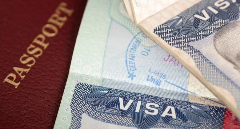 US-Einwanderungsdokumente, darunter ein Visum, eine Sozialversicherungskarte und eine Green Card, vor einer amerikanischen Flagge — symbolisieren die Arbeitserlaubnis und den H-1B-Visumsprozess.