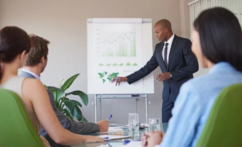 Graphic showing a business leader presenting global expansion strategies on a chart to employees in a boardroom meeting.