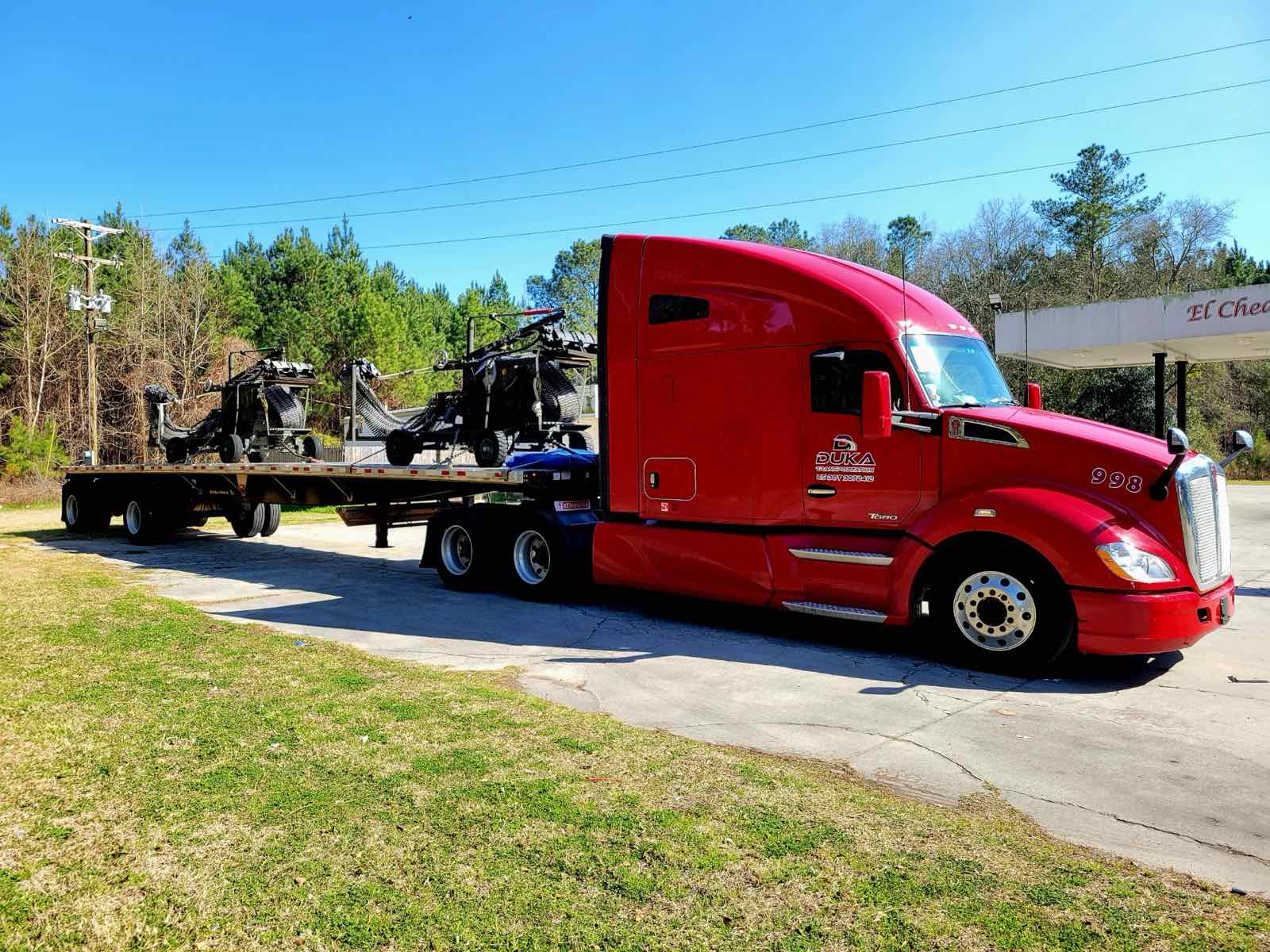 Red Duka Transportation semi-truck with flatbed trailer outdoors
