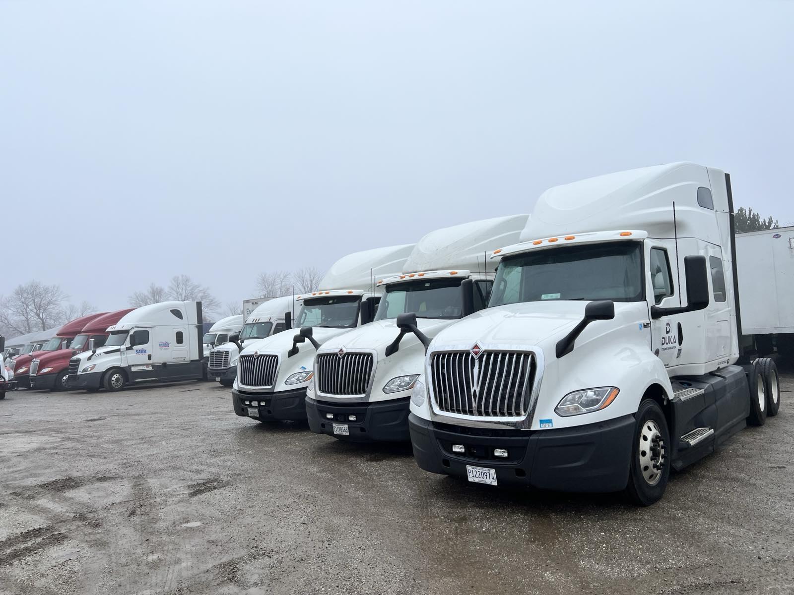 Fleet of Duka Transportation trucks parked in a row

