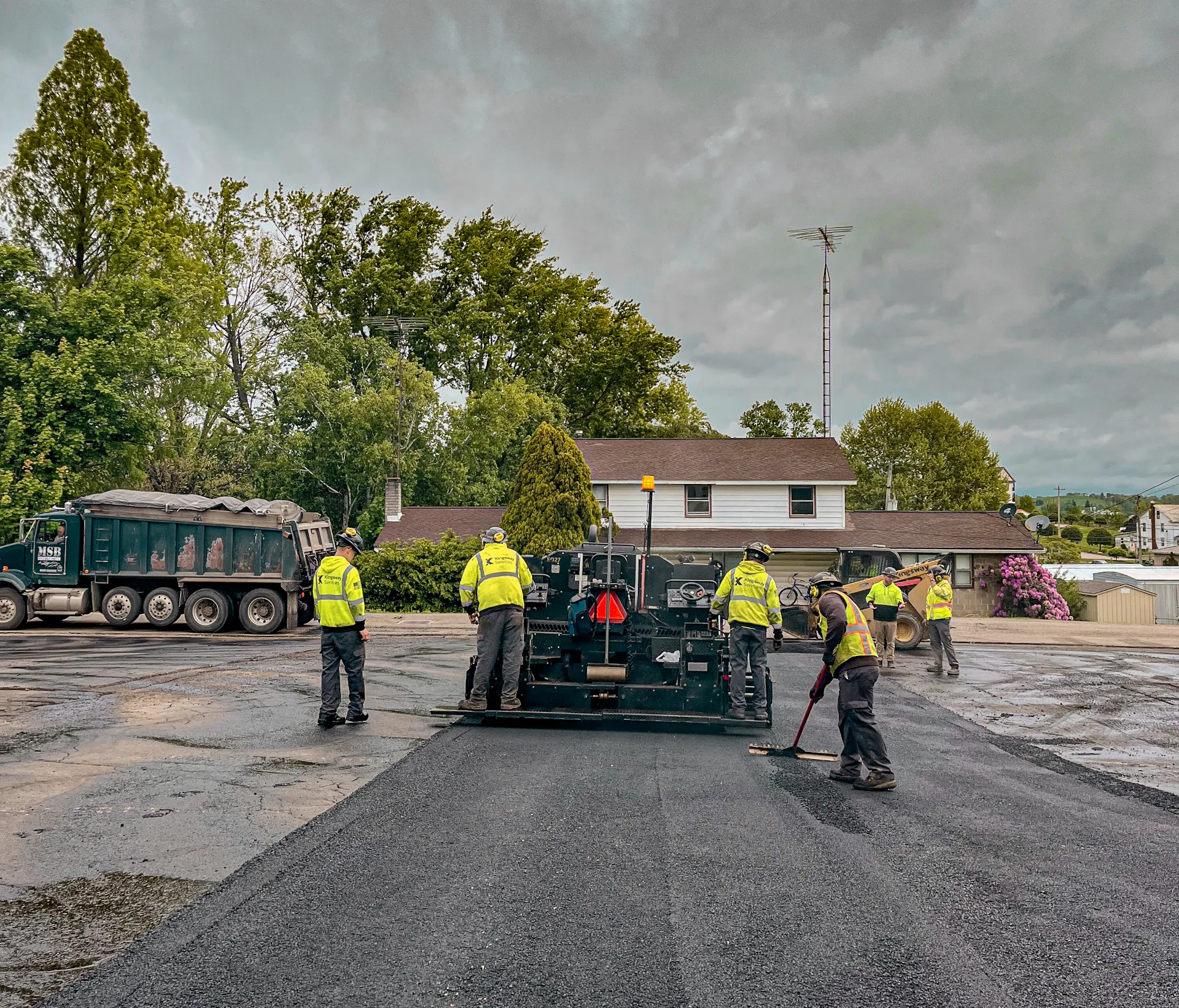 Commercial parking lot paving by Kingsway Services in Ohio, with an asphalt paving crew installing fresh asphalt using a paver and dump truck during a resurfacing project.