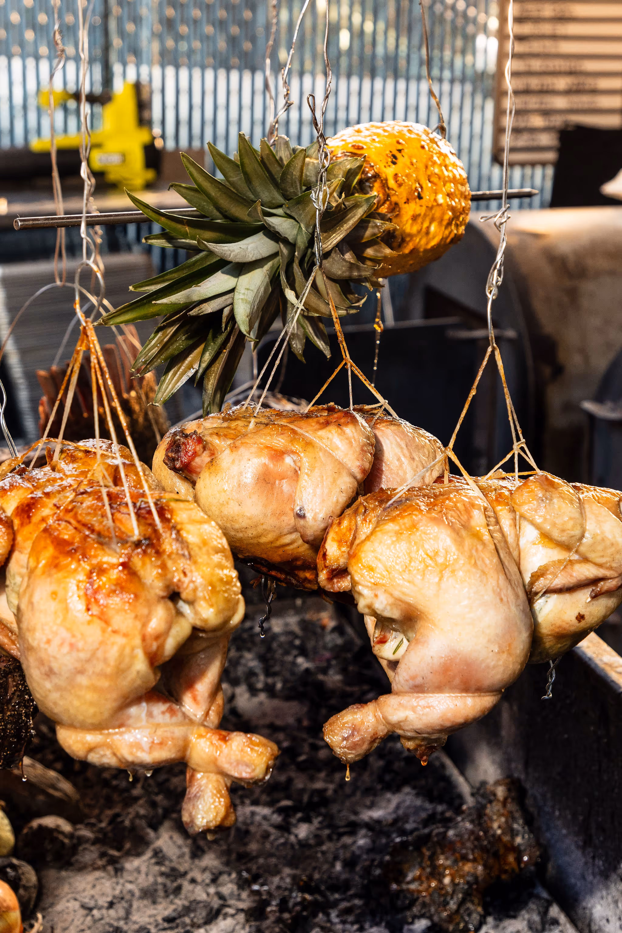 Whole chickens and pineapple roasting over coals on wire at 2Fifty BBQ in Washington D.C. by Sophie Mac Photo.