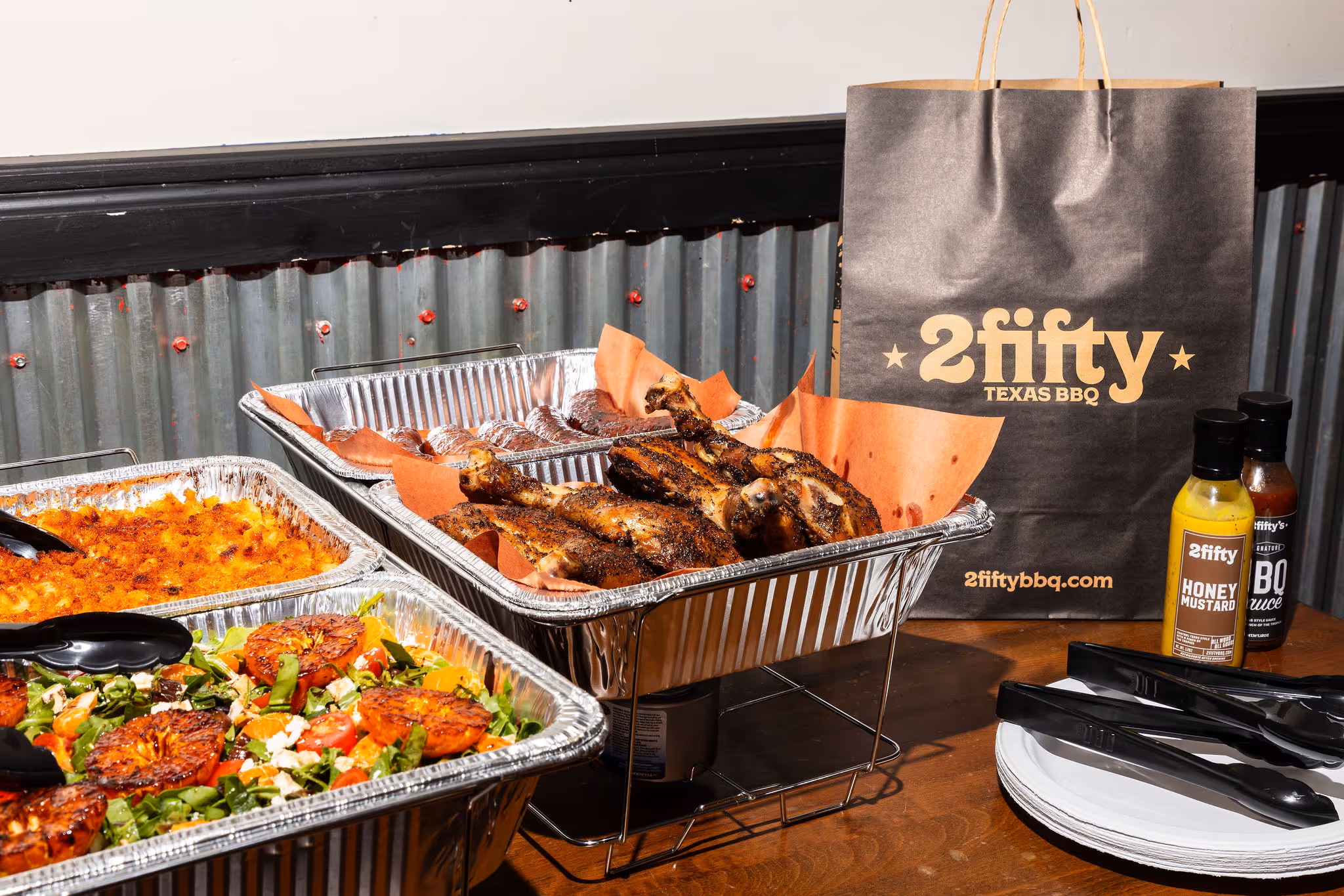 Catering setup with BBQ meats, sides, sauces, and branded bag at 2Fifty BBQ in Washington D.C. by Sophie Mac Photo.