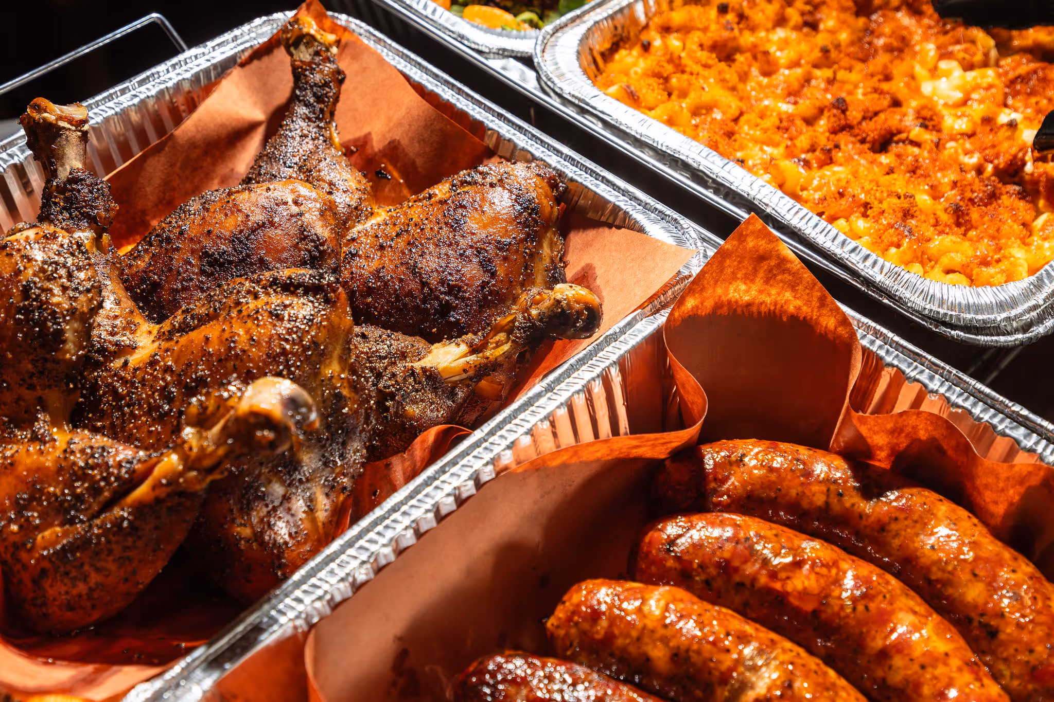 Catering trays with smoked chicken, sausages, and mac and cheese at 2Fifty BBQ in Washington D.C. by Sophie Mac Photo.