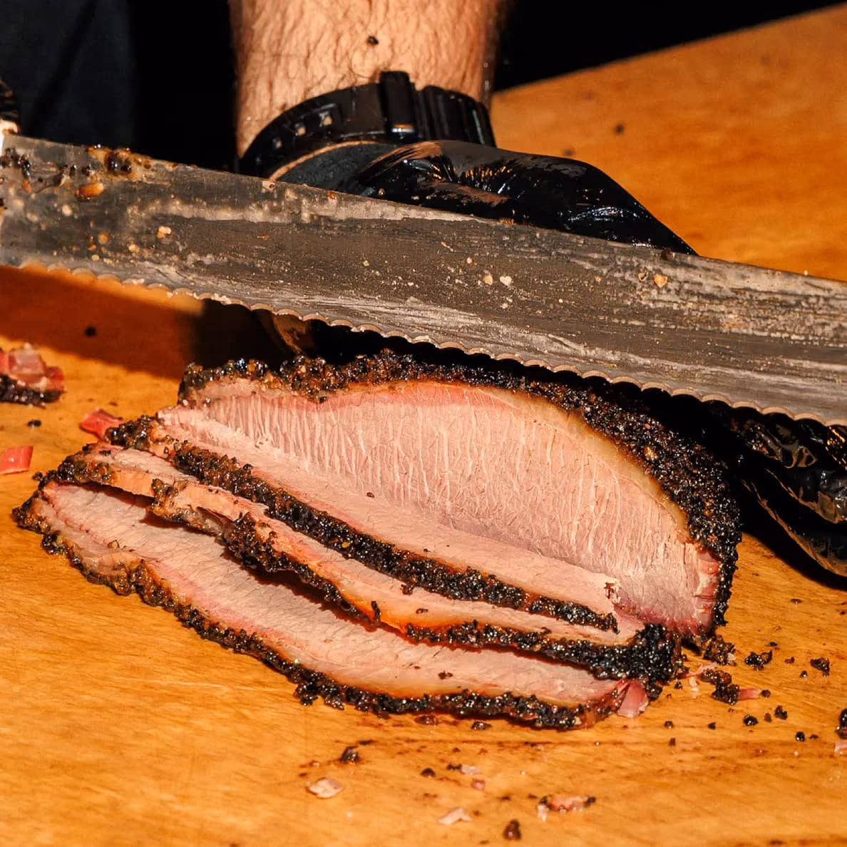 Prime brisket being sliced on a cutting board at 2Fifty BBQ, Texas-style wood-smoked barbecue