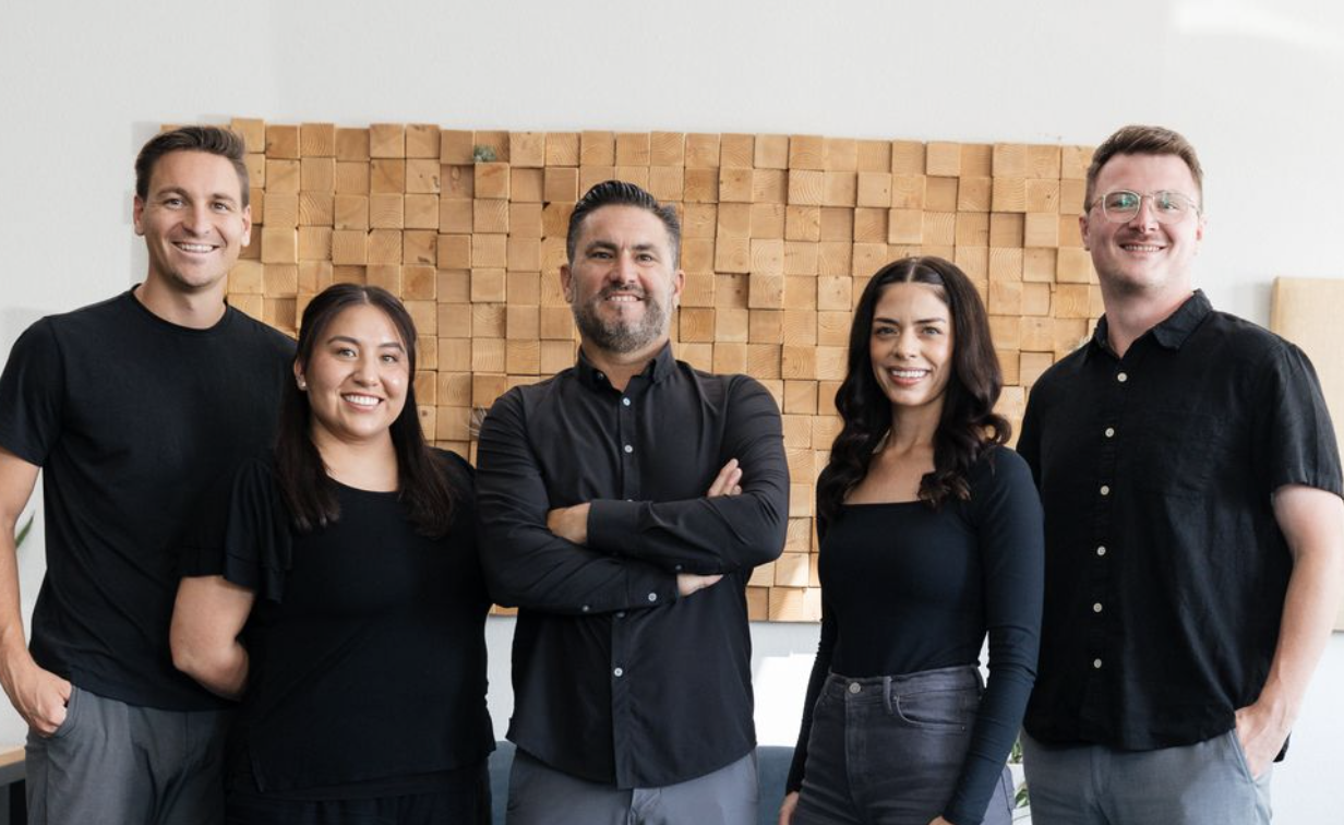 5 people with a dog standing in office
