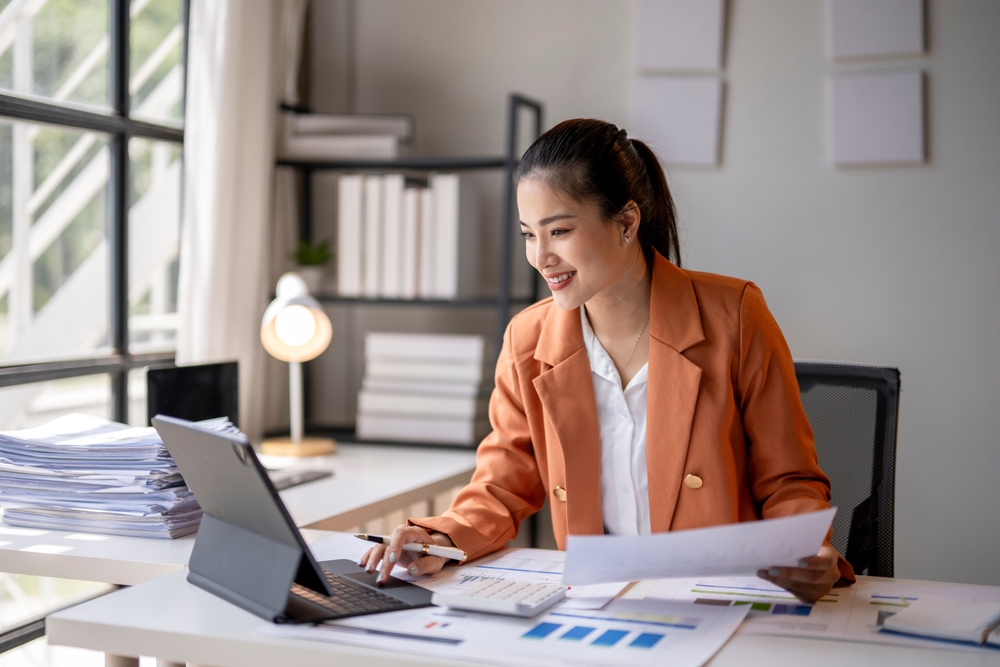 Professional woman reviewing money owed documents while verifying employment status, original creditor, and co signed details using telephone number records and home address.