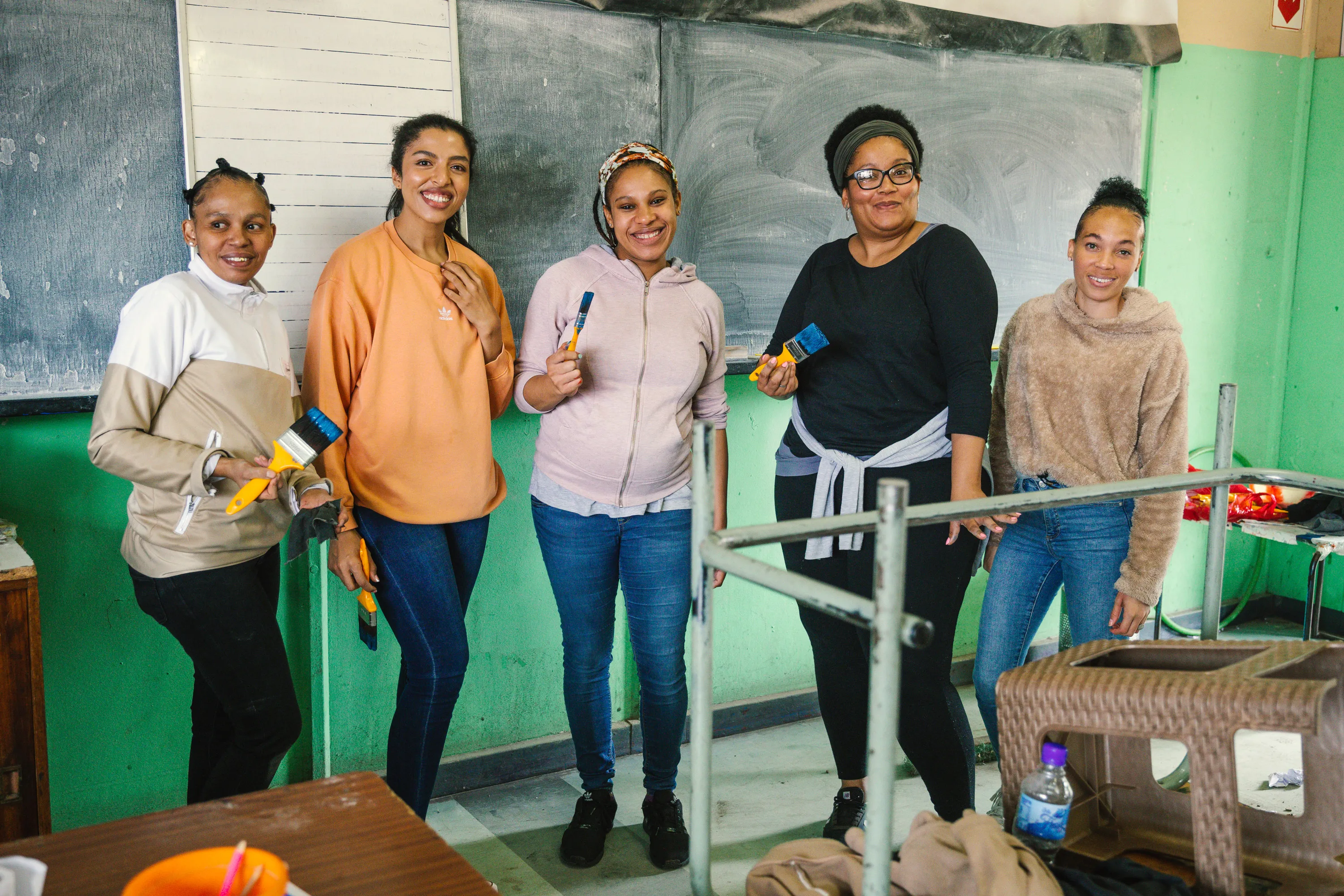 Five volunteers smiling while setting up a classroom.