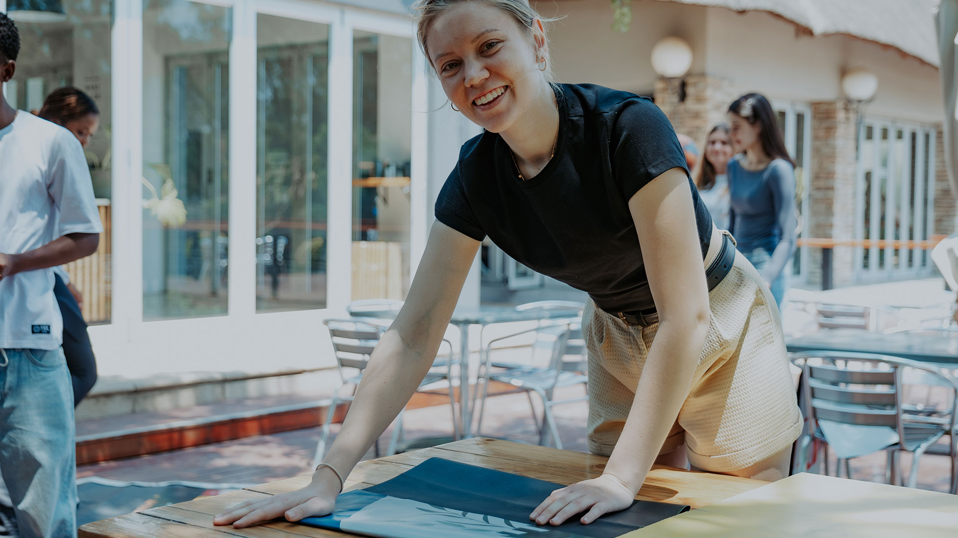 Volunteer smiling into camera while cutting cloth at a sewing event.