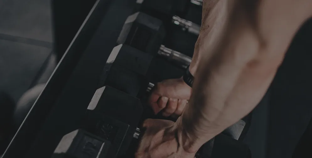 Close-up of a person gripping a dumbbell in a gym setting.