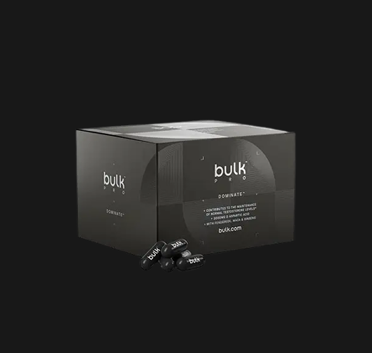 Black Bulk Pro Dominate supplement box with black capsules placed in front on a black background.