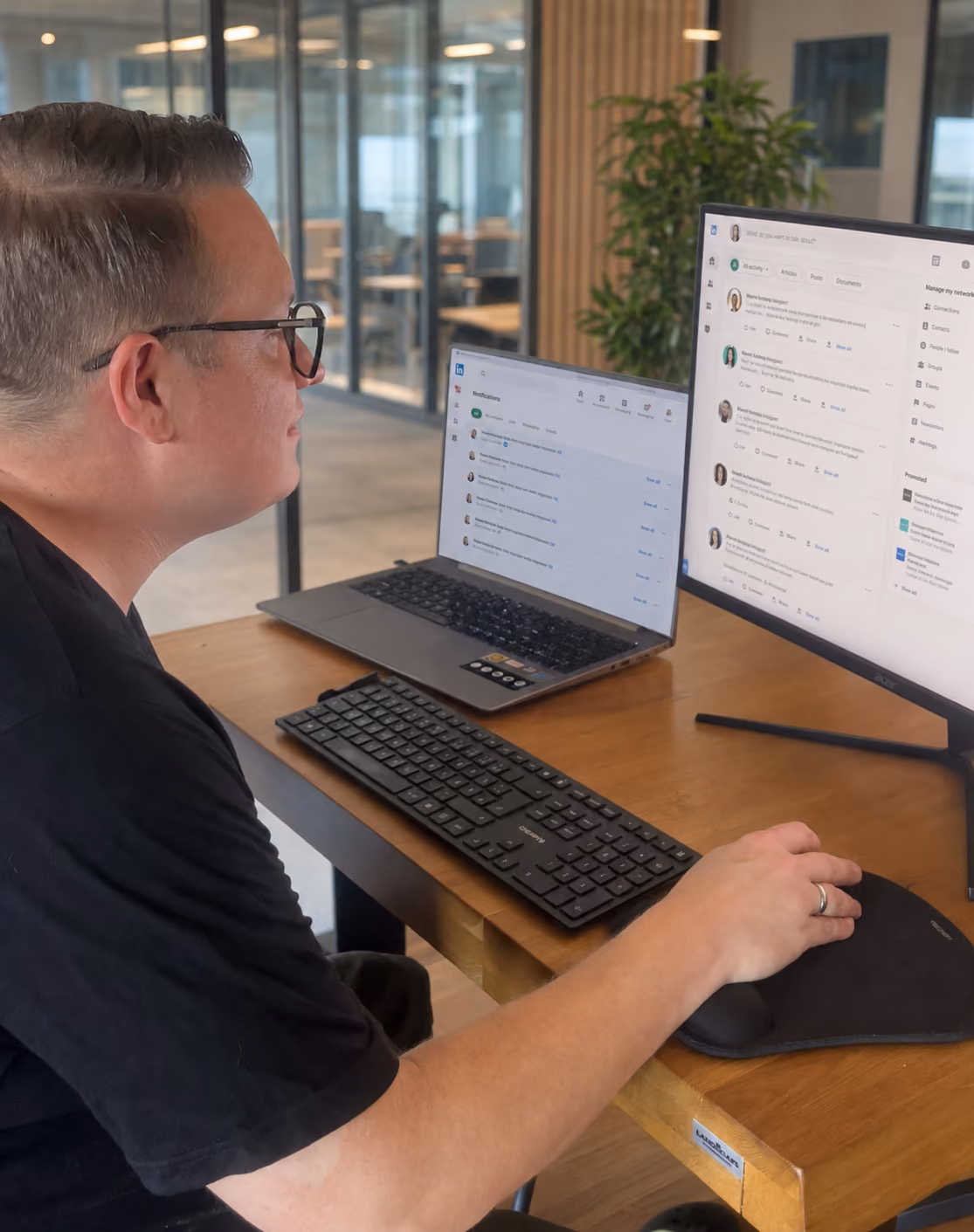 Alexander Spillmann bearbeitet im Büro LinkedIn-Mitteilungen, Kommentare und Netzwerkaktivitäten am Laptop und einem großen Monitor.
