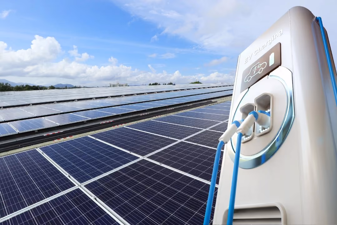 Vor einer Solaranlage ist auf der rechten Seite eine Ladesäule zu sehen.