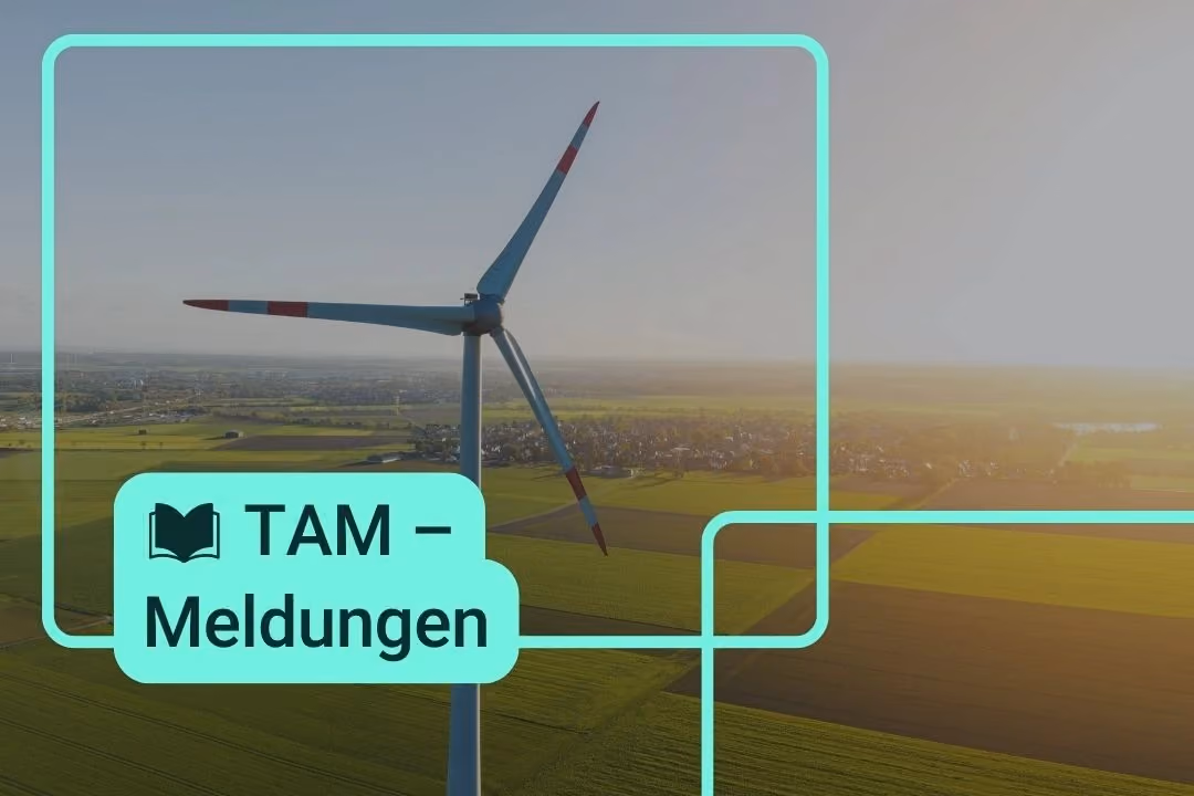 Ein Windkraftwerk steht auf einem Feld, beleuchtet von der untergehenden Sonne.