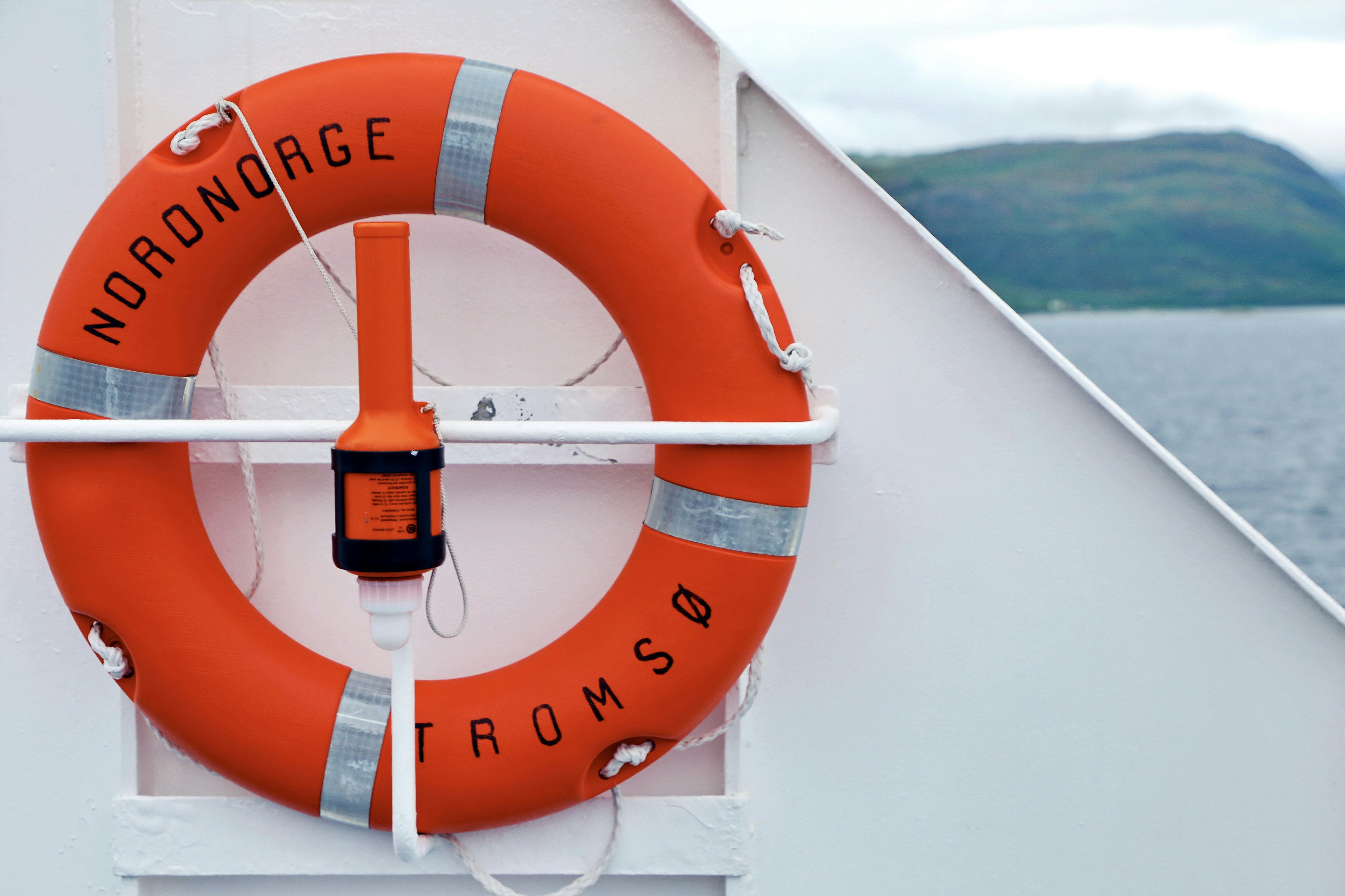 An orange life buoy is mounted on the side of a ship.