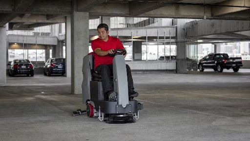 Commercial cleaning technician in red polo operating auto-scrubber in Class A Los Angeles parking structure