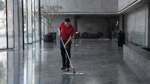 Commercial cleaning technician in red polo mopping the lobby floor of a Class A Los Angeles office building
