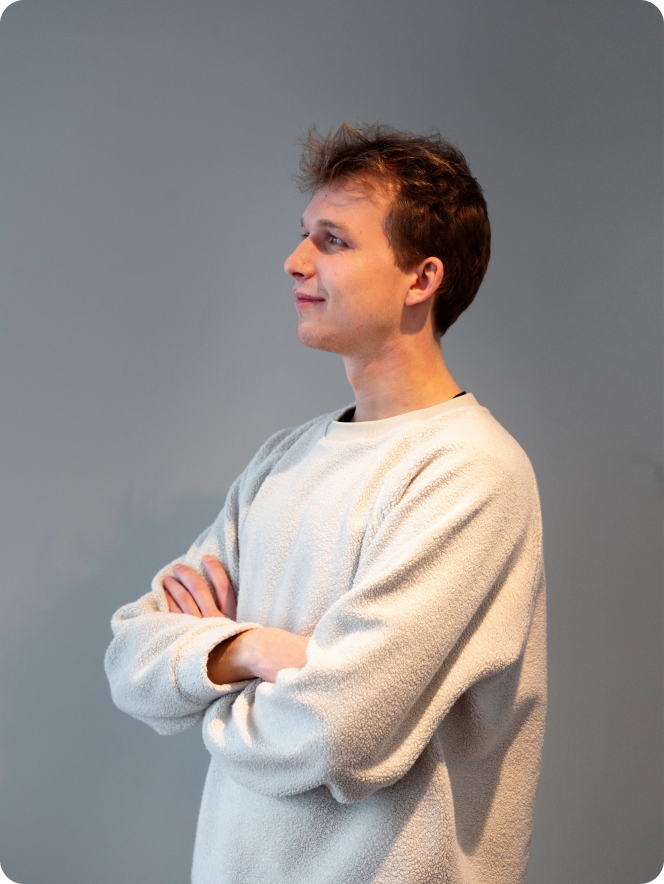 A man wearing a white sweater and looking at the camera.