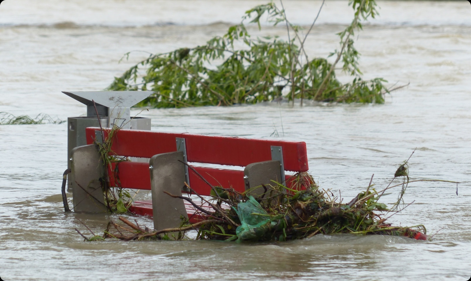 A red bench is submerged in a flood.