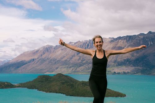 portrait of a woman with her arms spread in front of a mountain backdrop
