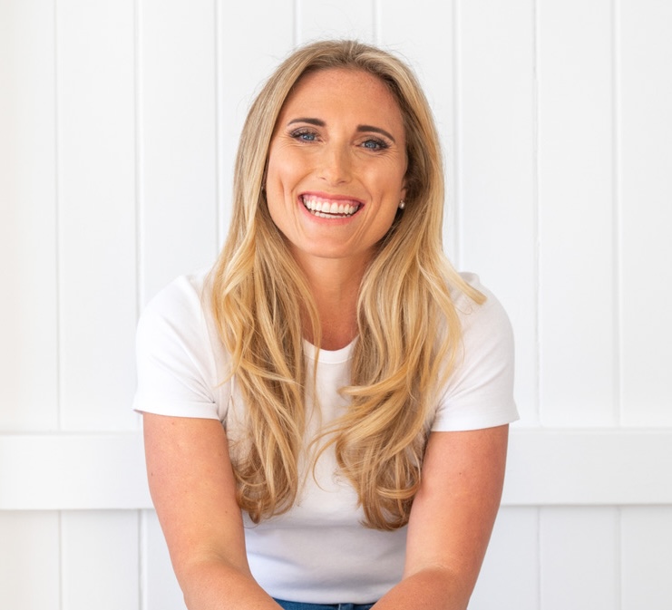 portrait of a white woman in a white top smiling at the camera