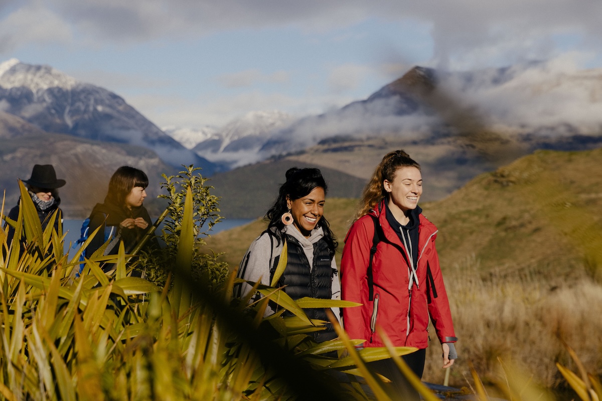 two woman walk down a walking path amongst nature
