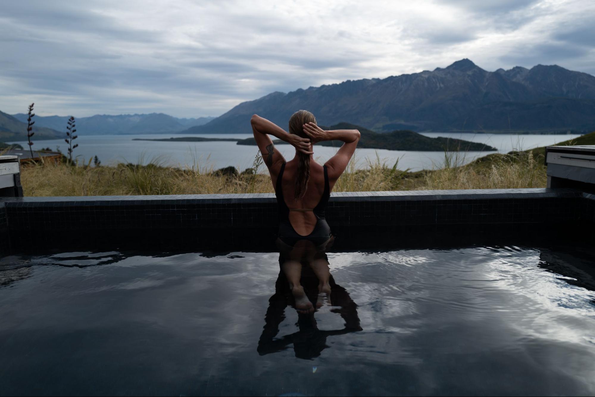 a woman looks at a mountain from a spa pool