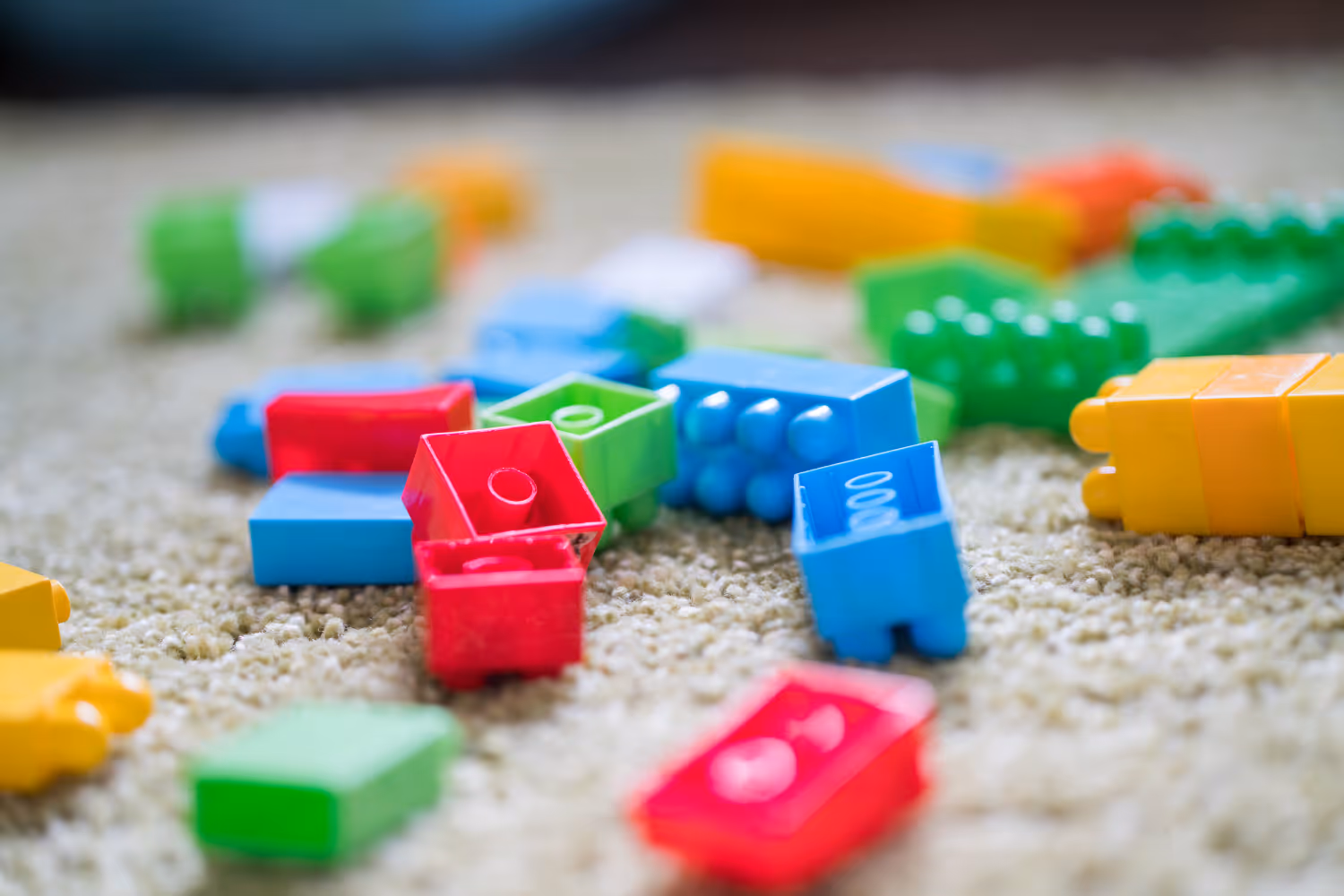 Pile of multicoloured LEGO blocks on a carpeted floor