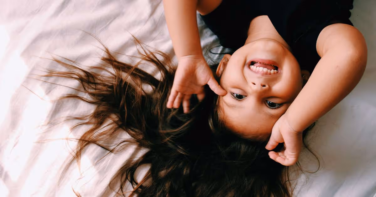 little girl playfully waving above her