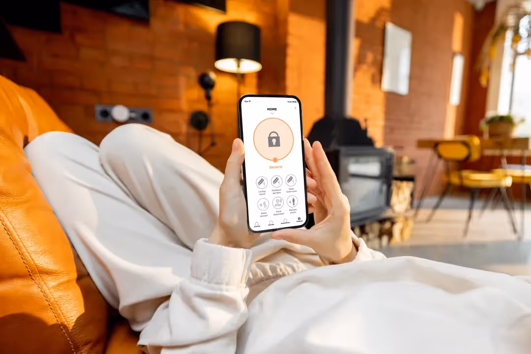young female holding up a smart phone with home security app active