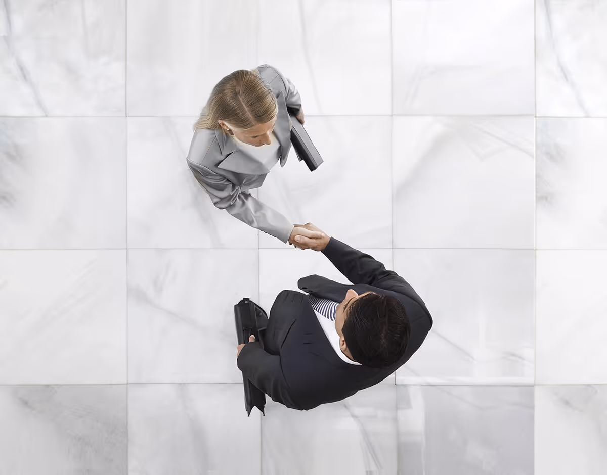 aerial view of two professionals shaking hands while standing on marble floor