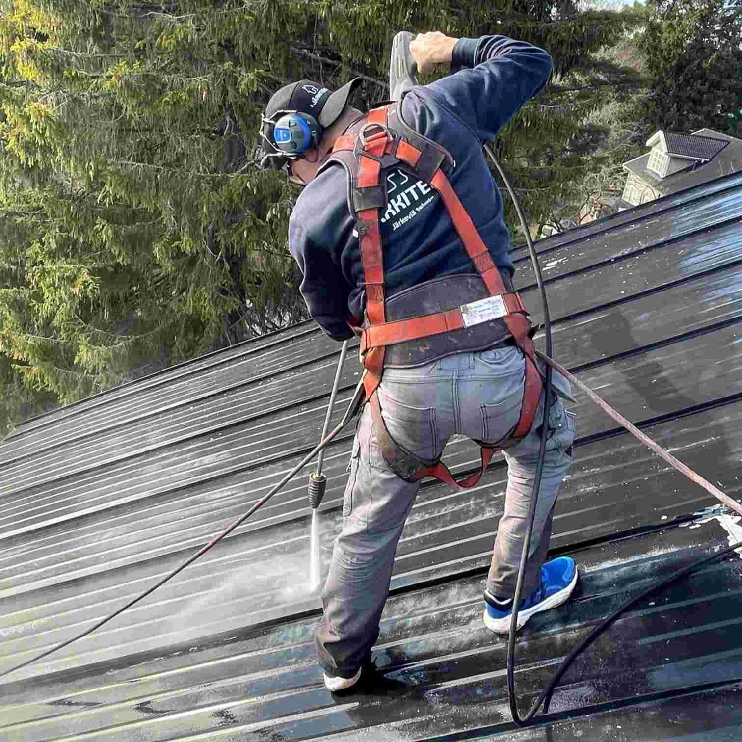 Järkiteon maalari pesemässä peltikattoa ruiskun avulla