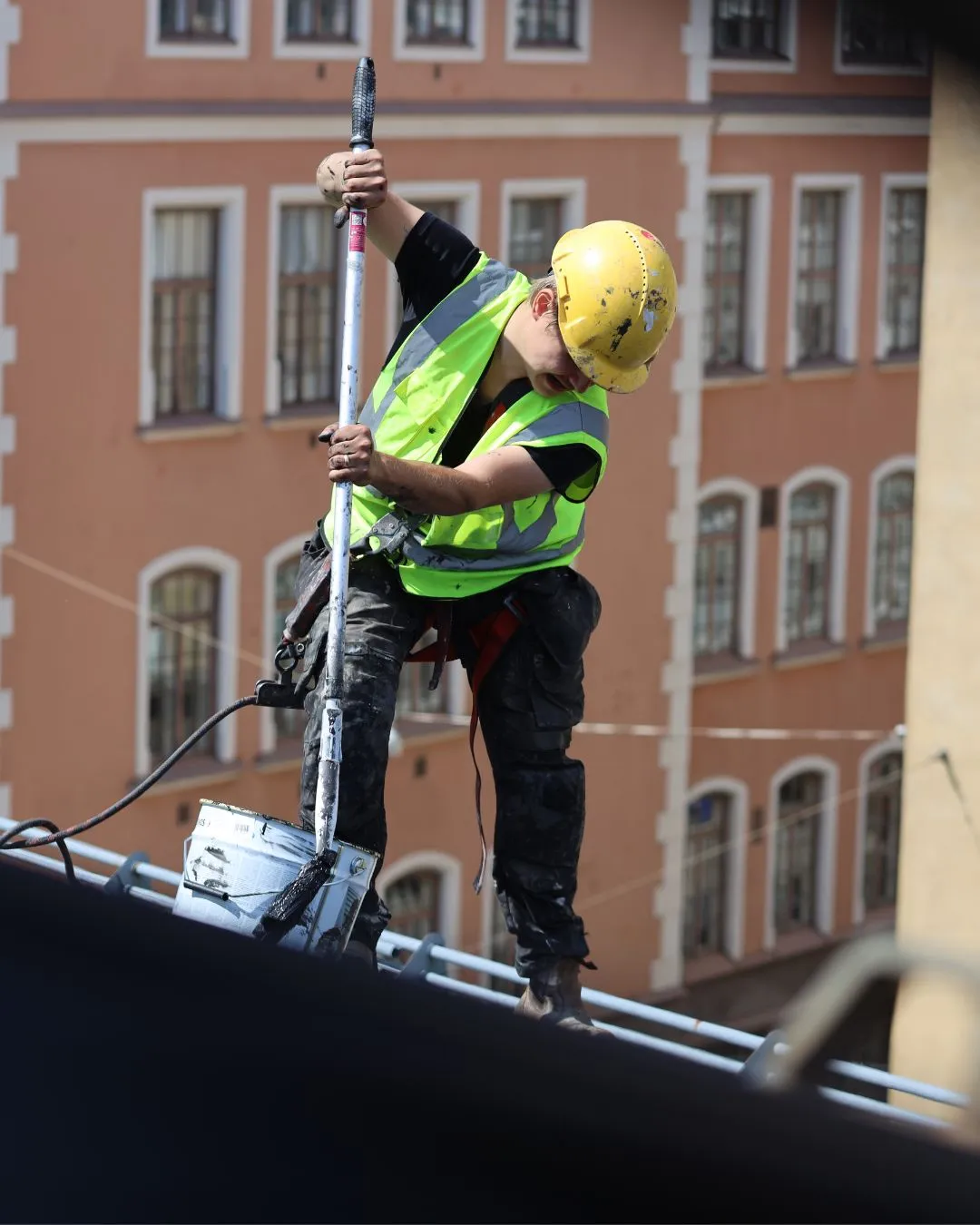 Peltikaton maalaus käynnissä - maalari maalaa peltikattoa turvavaljaissa