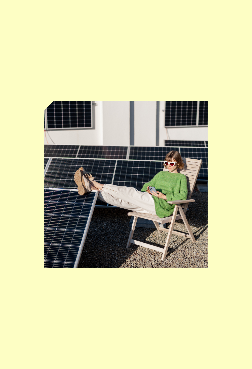 Woman in green sweater and white sunglasses relaxing on chair with feet on solar panel.