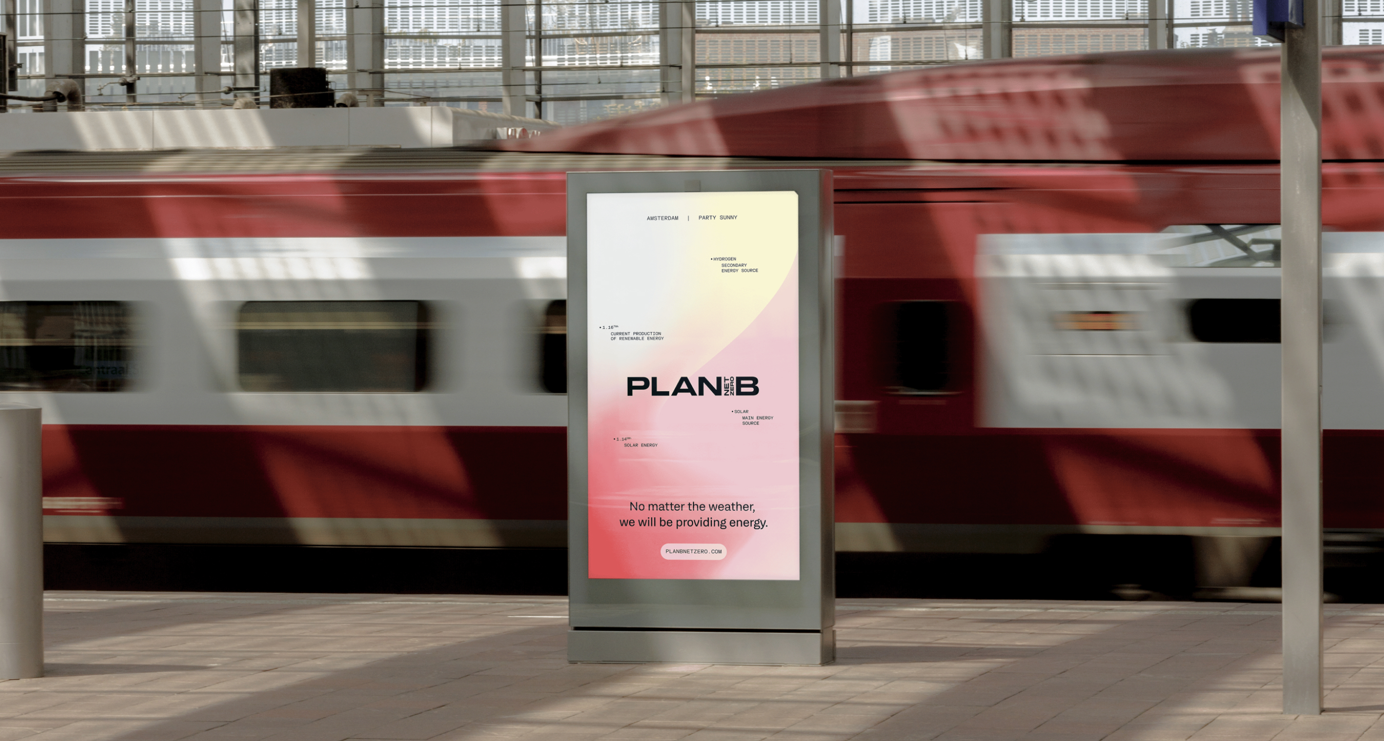 Digital billboard at train station shows Plan B energy message with red and white train passing by.
